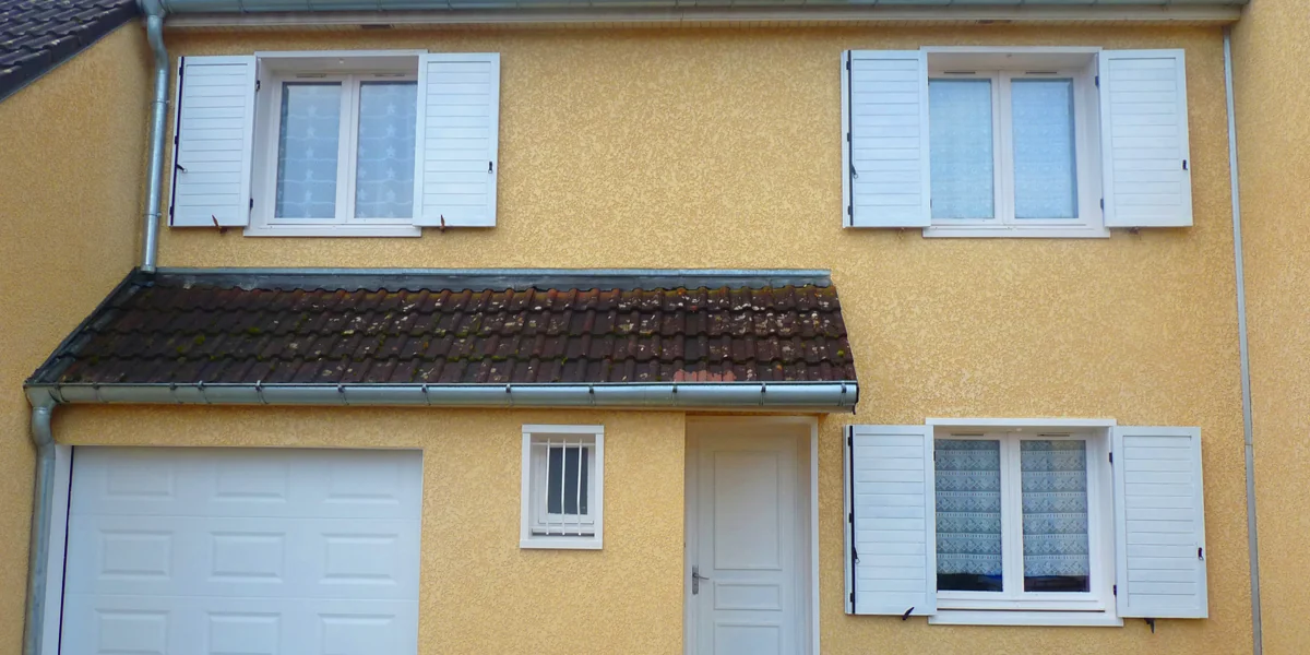Maison à façade ocre et volets blancs
